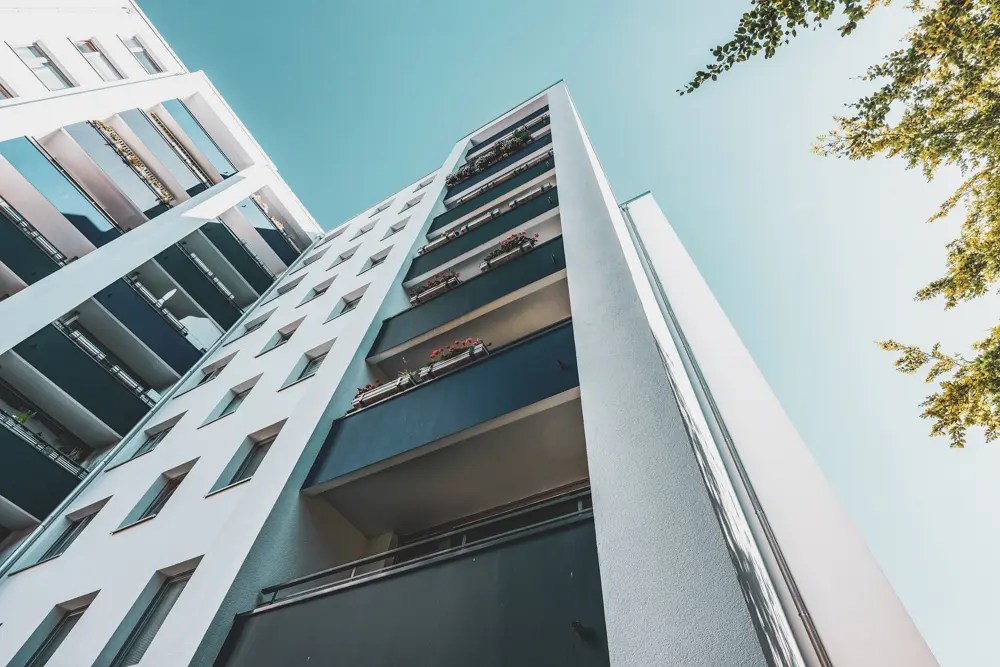 Der Blick von schräg unten auf ein Hochhaus in Hamburg, das von Maler Juergens saniert wurde – die gereinigte Fassade und Balkone sind im Vordergrund.